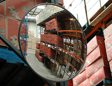Indoor convex safety mirror mounted in a warehouse aisle reflecting stacked boxes